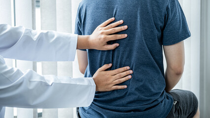 Female physiotherapist is checking spine of patient to doing healing treatment and rehabilitation injured back
