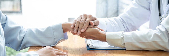 Male doctor hold hand patient to encourage and explaining treatment after writing prescription on clipboard