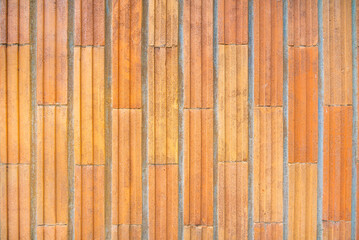 Background of narrow orange tiles with grooves laid vertically on the wall