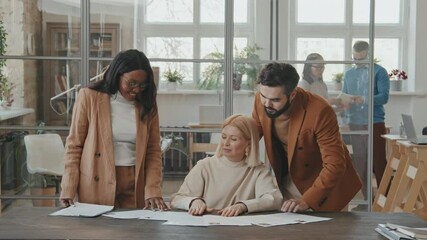 Tracking shot portrait of female HR manager, businesswoman and businessman looking at application forms and discussing possible job candidates in office, then looking up at camera and posing