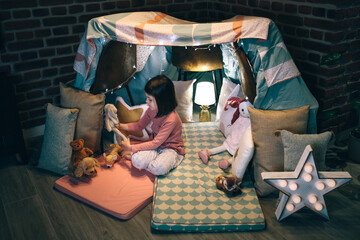Adorable girl playing alone with teddies in a tent made of bed sheets and chairs © David Pereiras
