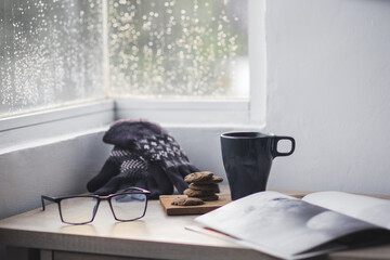 Winter gloves and beanie with a cup of coffee and cookie on wooden table for winter background