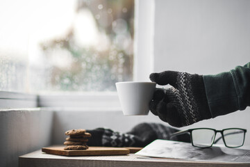 Hands with winter gloves holding a cup of coffee
