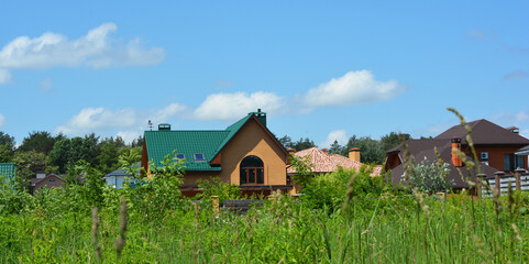 A brick cottage house with a green metal roof built in the picturesque place near a meadow and a...
