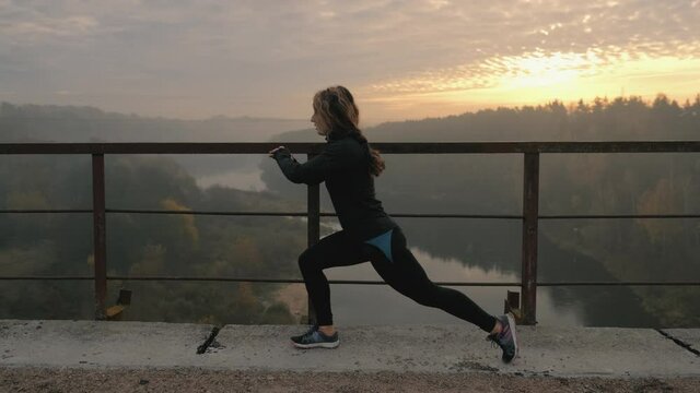 Runner woman is stretching legs with lunge hamstring stretch exercise leg stretches. Fitness female athlete is doing a warm-up before her strength training cardio workout.