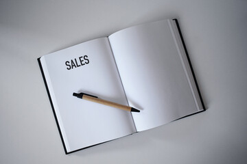 Book with pen on desk with sales heading