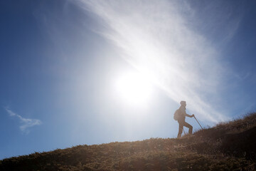 Young woman hiker with a backpack on the top of the mountain