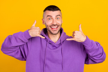 Photo portrait young man wearing violet sportswear showing sign call me sign isolated vibrant yellow color background