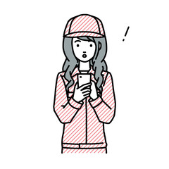 立ってスマートフォンを操作して何かに気づいて驚いた作業員の女性