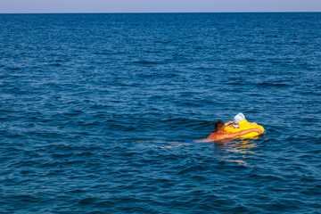 A man and a little girl swim with inflatable coils in the sea water and are hit by a big wave in turkey. Holidays, travel, childhood - concept