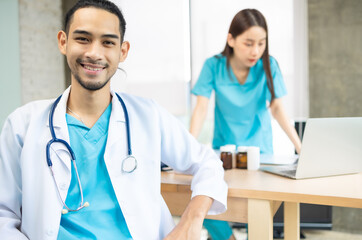 Confident young Asia female doctor in white medical uniform with stethoscope looking at camera and smiling while video conference call with patient in health hospital.