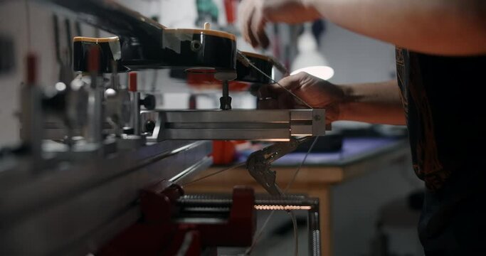Luthier mounts the electric guitar on the jig at the musical instruments repairing shop, 4k 60p 10 bit