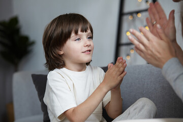 Happy mother and son clapping hand partnership friendship family weekend at home. Woman babysitter...
