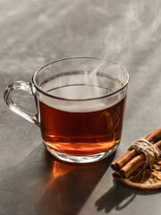 Hot steaming tea in a transparent cup. Cinnamon.