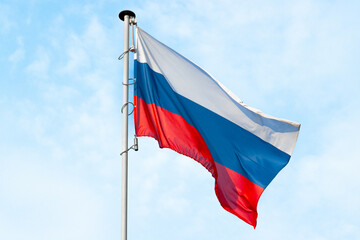 National flag of Russia on a pole against against light blue sky background