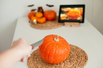 watching a tutorial on tablet about making jack-o-lantern out of a pumpkin