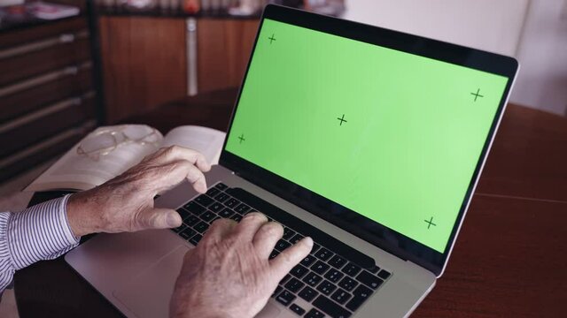Old Italian author and university professor in retirement typing on computer keyboard with green screen chroma key, senior writer planning book story and writing down for publication. Old Italian man