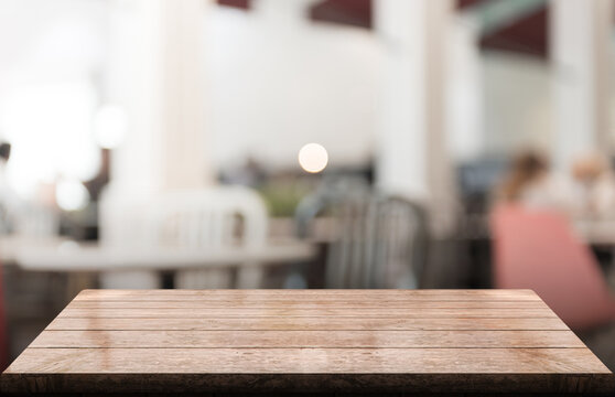 Empty wooden table top with lights bokeh on blur restaurant background.