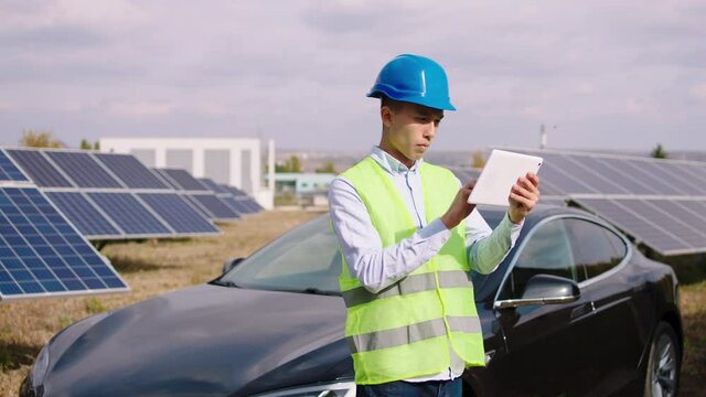 Ecological Engineer Man Asian Looking Using Digital Tablet To Controlling The Photovoltaic Batteries At Solar Panels Power Station. Shot On ARRI Alexa Mini.