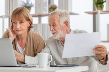 Worried senior couple checking their bills, retired elderly old family reading documents