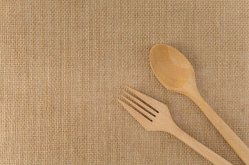 Top view brown wooden fork spoon on the burlap fabric.