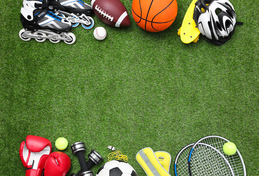 Different sport equipment on green grass, flat lay. Space for text © New Africa