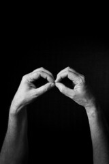 B+W image of hand demonstrating BSL sign language letter B isolated against black background