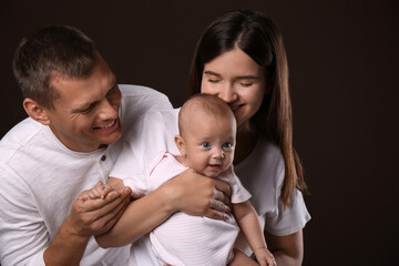 Happy family with little baby on dark background