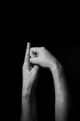 B+W image of hand demonstrating BSL sign language letter K isolated against black background