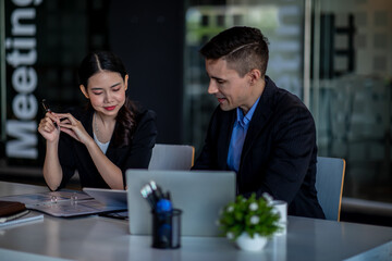 Business people working together. Serious businessman with laptop talking to a businesswoman with papers and tablet. Business partners have a successful meeting in the modern office.