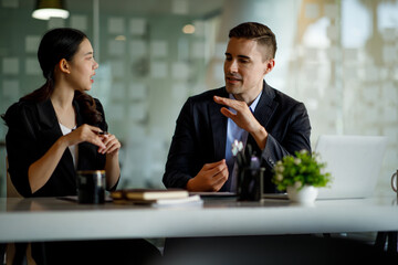 Business people working together. Serious businessman with laptop talking to a businesswoman with papers and tablet. Business partners have a successful meeting in the modern office.
