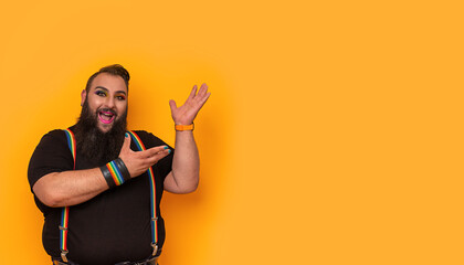 Happy bearded gay big man with rainbow trouser holder pointing side-up
