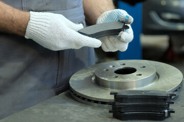 Spare parts. A brake disc and a set of brake pads. Close-up. Inspection of spare parts during the...