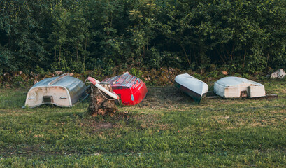 Boats lie upside down on the grass by a lake