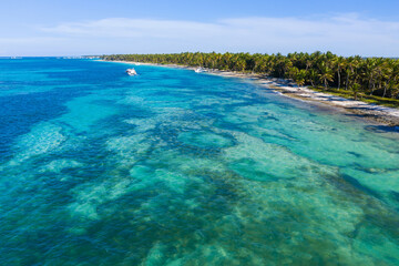 Speed boat floating along tropical island with palm trees near caribbean sea. Dominican Republic. Aerial view