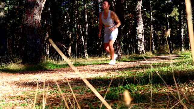 video of sporty girl running through nature and getting injured while exercising