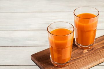 Two glasses of pumpkin juice on white wooden background. Vegetable detox drink for healthy diet.