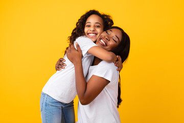 African American girl hugging her smiling mom at studio
