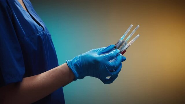Doctor holding syringes with solutions. Nurse wearing protective white gloves showing samples of medicine, vaccination against covid-19, laboratory research concept. Coronavirus vaccine.
