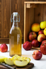 Bottle of apple cider vinegar on background of box with apples and fresh chopped apples