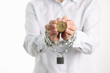 Woman with tied metal chain hands holding bitcoin coin closeup