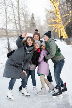 Happy Family Taking Selfie While Ice Skating In Winter Park