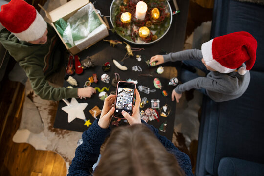 Girl with camera phone photographing brothers with Christmas ornaments