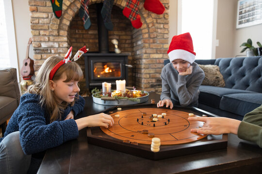 Brother and sister in Santa hats playing Crokinole in living room