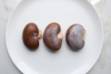 Wide shot of kidneys on a white plate.