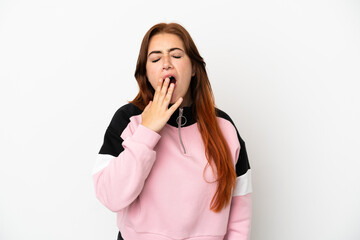 Young redhead woman isolated on white background yawning and covering wide open mouth with hand