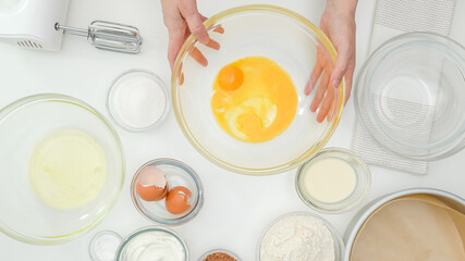 Egg yolks, egg whites, flour, sugar, and some ingredients for cake recipe close up on kitchen table. Homemade chocolate cake step by step baking process