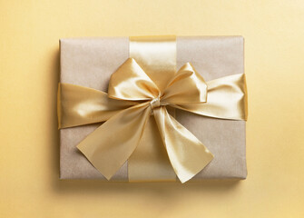 Gift box with bow on golden background. Christmas, New year or birthday present. Top view, flat lay
