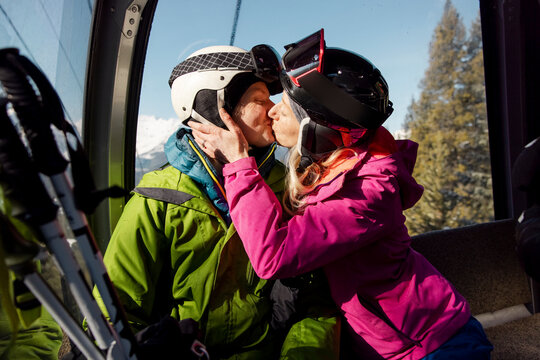 Affectionate skier couple kissing in ski lift gondola