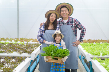 Happy farmer family working in hydroponic greenhouse farm, clean food and healthy eating concept